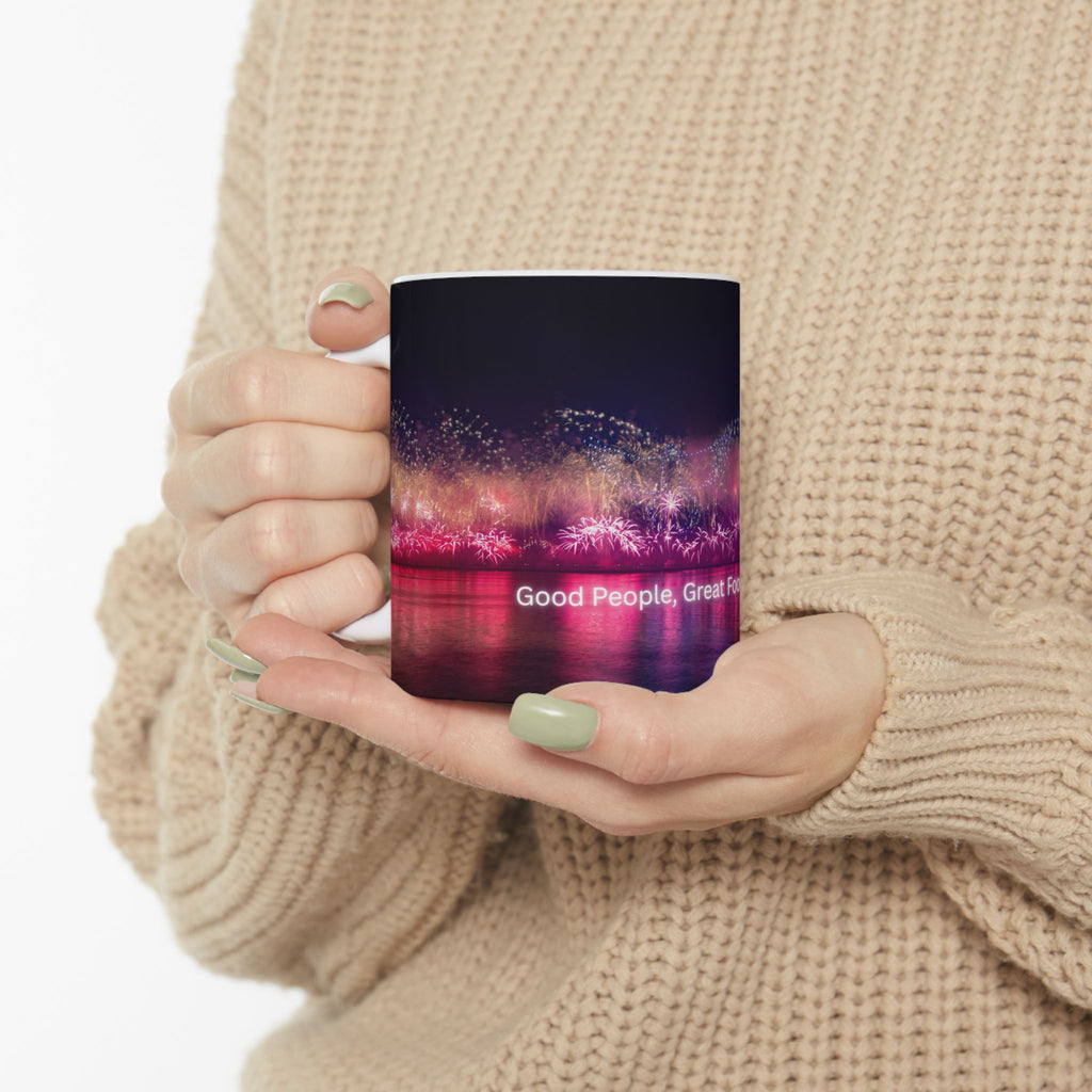 Ceramic mug with neon nightscape fireworks and partial quote on front, held by hand