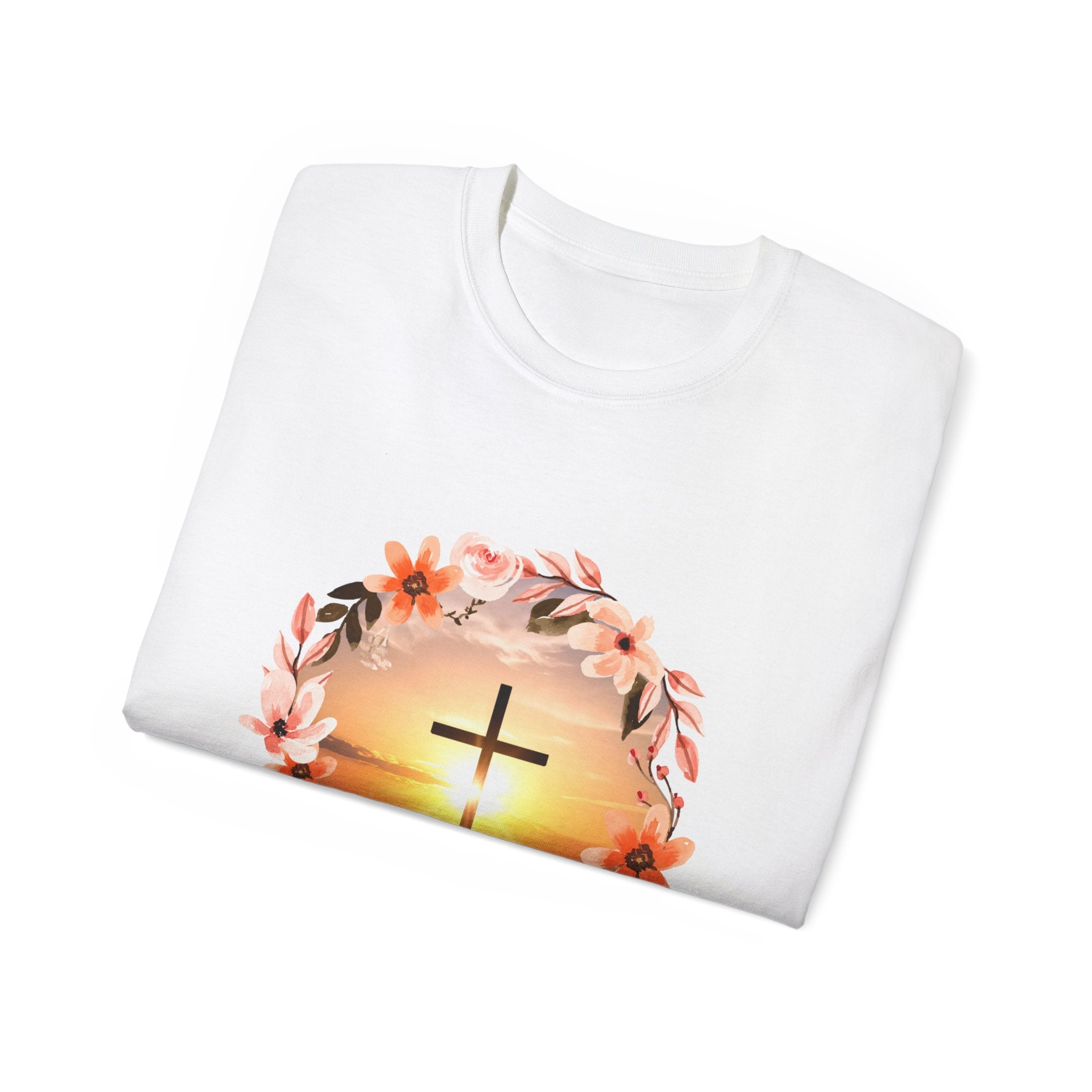White crew-neck T-shirt with floral wreath sunset and gold cross graphic, folded