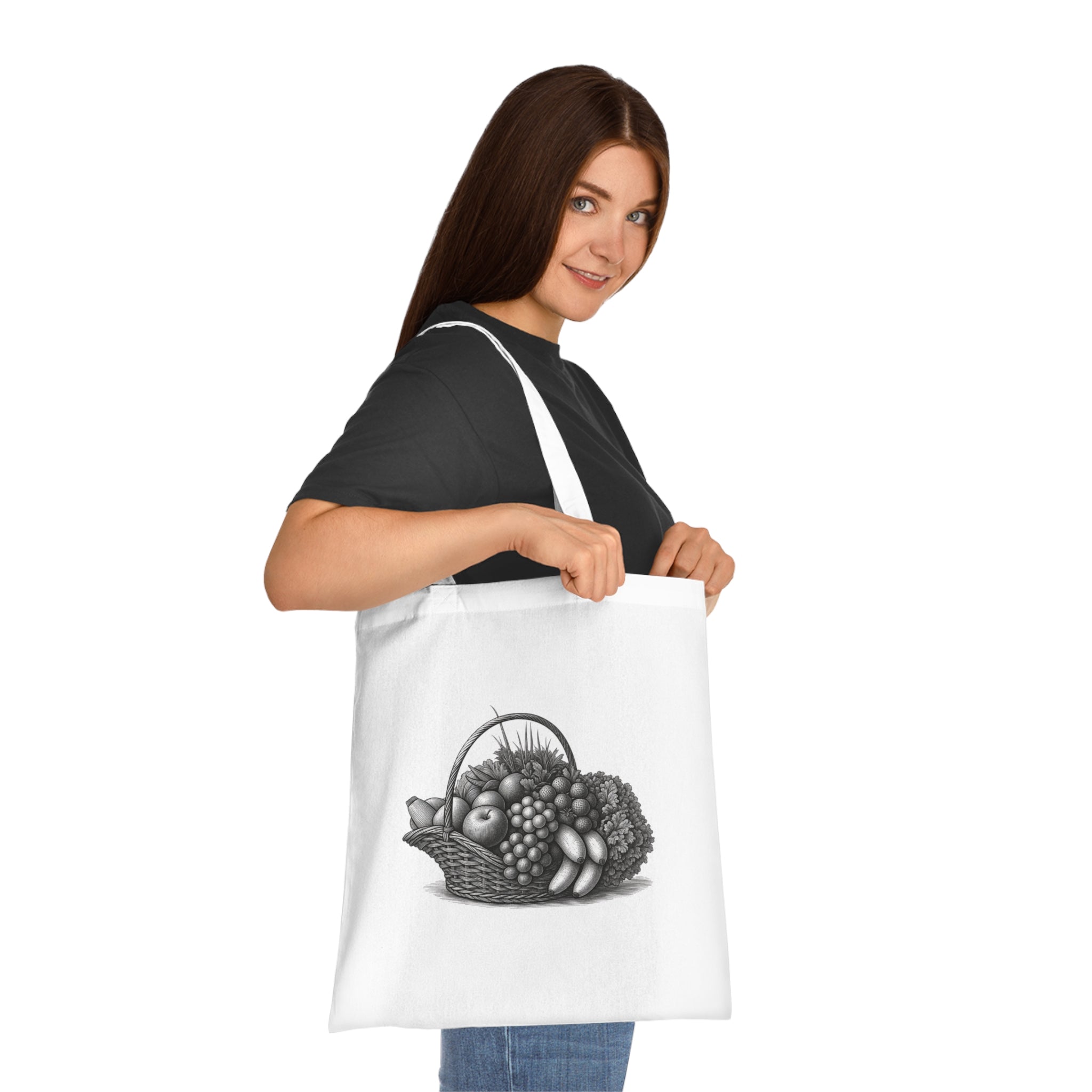 White cotton tote bag held by model, fruit basket graphic on front