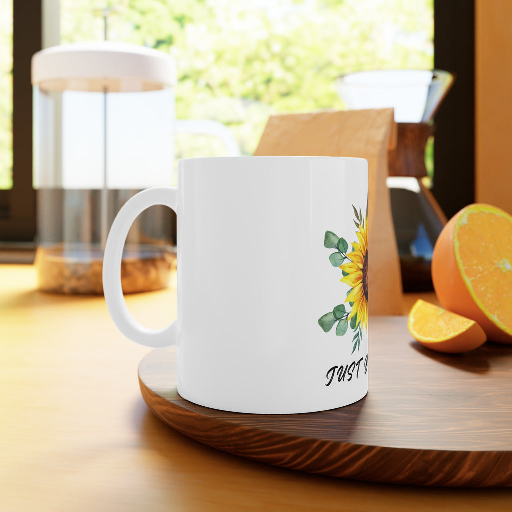 White ceramic mug with sunflower design near the handle and “Just Breathe” script
