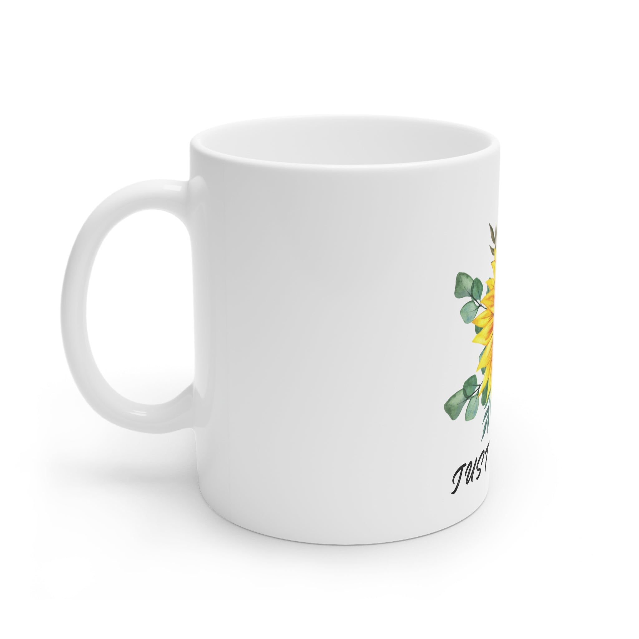 White ceramic mug with side sunflower artwork and partial “Just B…” lettering